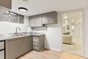 Kitchen with gray cabinets, light wood-style flooring, and light countertops