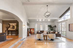 Living room with vaulted ceiling, plenty of natural light, french doors, arched walkways, and hanging lights