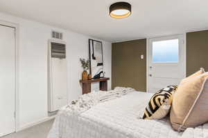 Bedroom with a heating unit and light colored carpet