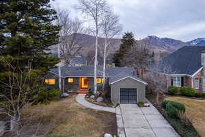 View of front facade with driveway, a mountain view, brick siding, and an attached garage