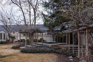 Back of house featuring a hot tub, a fenced backyard, and a wooden deck