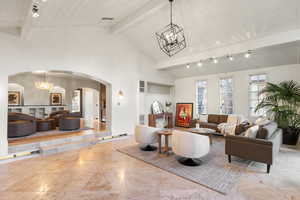 Living area featuring hanging lights, arched walkways, and a high wood beamed ceiling