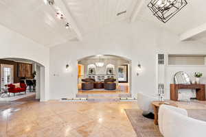Foyer with a chandelier, arched walkways, a heating unit, and a high wooden beamed ceiling