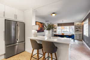 Kitchen with freestanding refrigerator, a breakfast bar area, built in features, decorative light fixtures, and crown molding