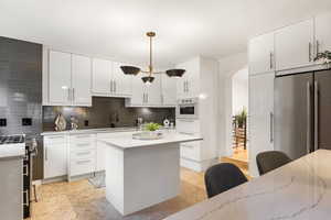 Kitchen featuring arched walkways, white cabinetry, and hanging light fixtures