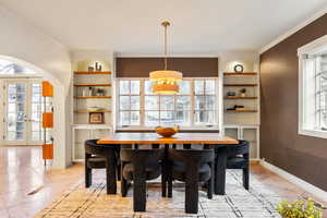 Dining area with french doors, arched walkways, built in shelves, and crown molding