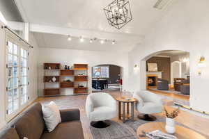Tiled living area with suspended lighting, lofted ceiling, a lit fireplace, and arched walkways