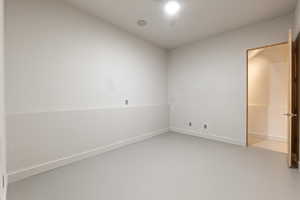 Empty room featuring concrete flooring and baseboards