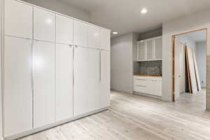 Kitchen with white cabinets, glass fronted cabinets, light wood-style flooring, tasteful backsplash, and recessed lighting