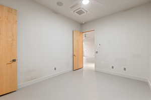 Spare room featuring concrete flooring, cooling unit, and ceiling fan