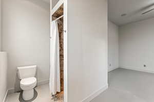 Full bathroom featuring a shower with curtain, finished concrete flooring, and a ceiling fan