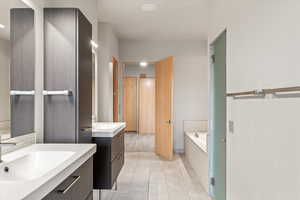 Full bathroom with a garden tub, two vanities, and light tile patterned floors