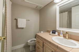Full bathroom featuring vanity, curtained shower, and light tile patterned flooring
