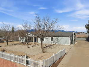 Single story home featuring a fenced front yard, covered porch, and a mountain view