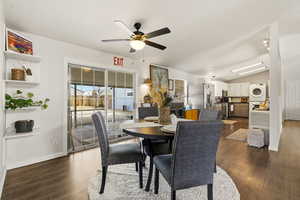 Dining area featuring vaulted ceiling, dark wood finished floors, ceiling fan, and stacked washing machine and dryer
