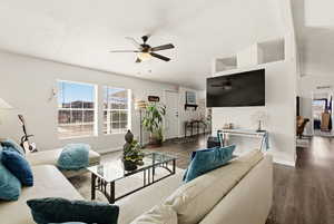 Living room with dark wood-style flooring, a ceiling fan, and lofted ceiling