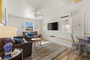 Living area with lofted ceiling, light wood finished floors, and ceiling fan