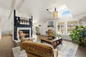 Living room with vaulted ceiling, dark wood finished floors, and a glass covered fireplace