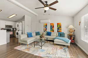 Living room with stacked washer and clothes dryer, ceiling fan, dark wood-type flooring, and beamed ceiling