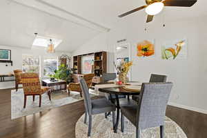 Dining room featuring beamed ceiling, dark wood finished floors, and a ceiling fan