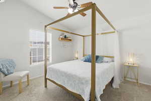 Bedroom featuring ceiling fan, vaulted ceiling, and light carpet