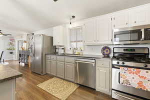 Two tone kitchen featuring stainless steel appliances, a ceiling fan, dark wood-style floors, tasteful backsplash, and two tone color scheme