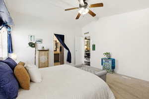 Carpeted bedroom with ceiling fan, lofted ceiling with beams, and connected bathroom