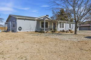 View of front facade featuring covered porch, crawl space, and a gate