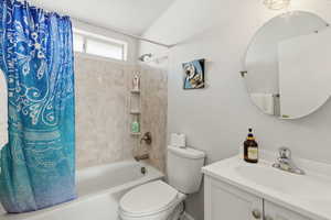 Bathroom with shower / bathtub combination with curtain, a textured wall, vanity, and a textured ceiling