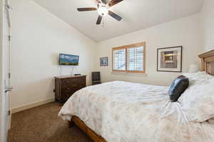 Bedroom featuring vaulted ceiling, dark carpet, and ceiling fan