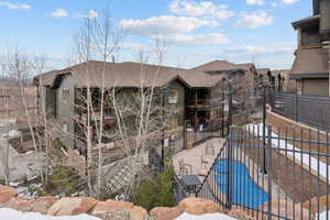 View of front of house featuring a community pool, a patio area, and a balcony