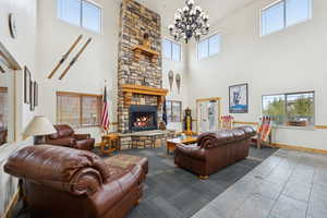 Living area with a fireplace, dark tile patterned flooring, a high ceiling, and a chandelier