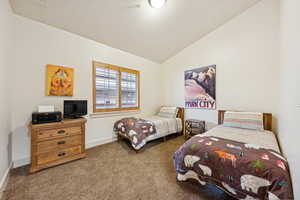 Carpeted bedroom with vaulted ceiling and baseboards