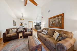 Living area with a ceiling fan, lofted ceiling, and light wood-style flooring
