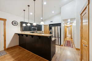 Kitchen with a kitchen breakfast bar, a peninsula, light stone countertops, decorative light fixtures, and stainless steel appliances