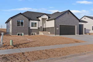 View of front facade with concrete driveway, brick siding, a garage, board and batten siding, and a shingled roof