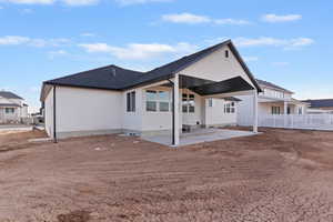 Rear view of property featuring a patio area, roof with shingles, and stucco siding