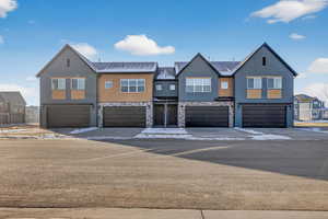 Craftsman house featuring a residential view, a garage, stone siding, and driveway
