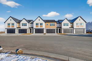 View of front of property with an attached garage, stone siding, and a residential view