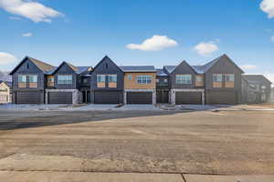 View of front of property with a residential view, stone siding, and a garage