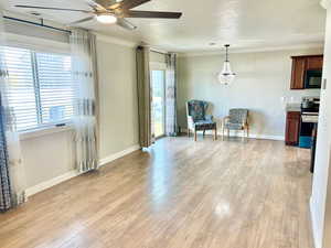 Sitting room featuring a ceiling fan, light wood finished floors, and crown molding
