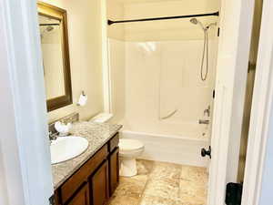 Full bathroom featuring vanity, bathing tub / shower combination, and light stone finish flooring