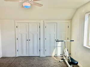 Exercise area with vaulted ceiling, ceiling fan, and carpet