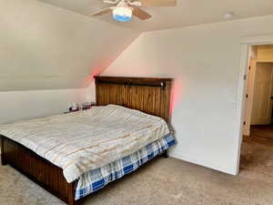 Bedroom featuring carpet flooring, vaulted ceiling, and a ceiling fan