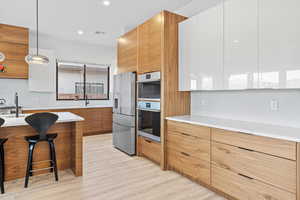 Two tone kitchen with modern cabinets, dual tone cabinets, backsplash, and decorative light fixtures
