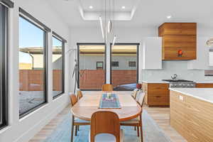 Dining room featuring light wood-style flooring, recessed lighting, and a tray ceiling