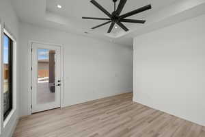 Unfurnished room with a raised ceiling, light wood-style flooring, a ceiling fan, and recessed lighting