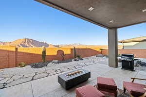 Fenced backyard featuring a patio, a mountain view, area for grilling, and an outdoor fire pit