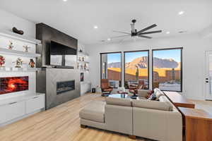 Living area with light wood-style flooring, a fireplace, ceiling fan, and recessed lighting