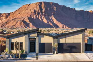 View of front of property with a mountain view, stucco siding, a garage, and driveway